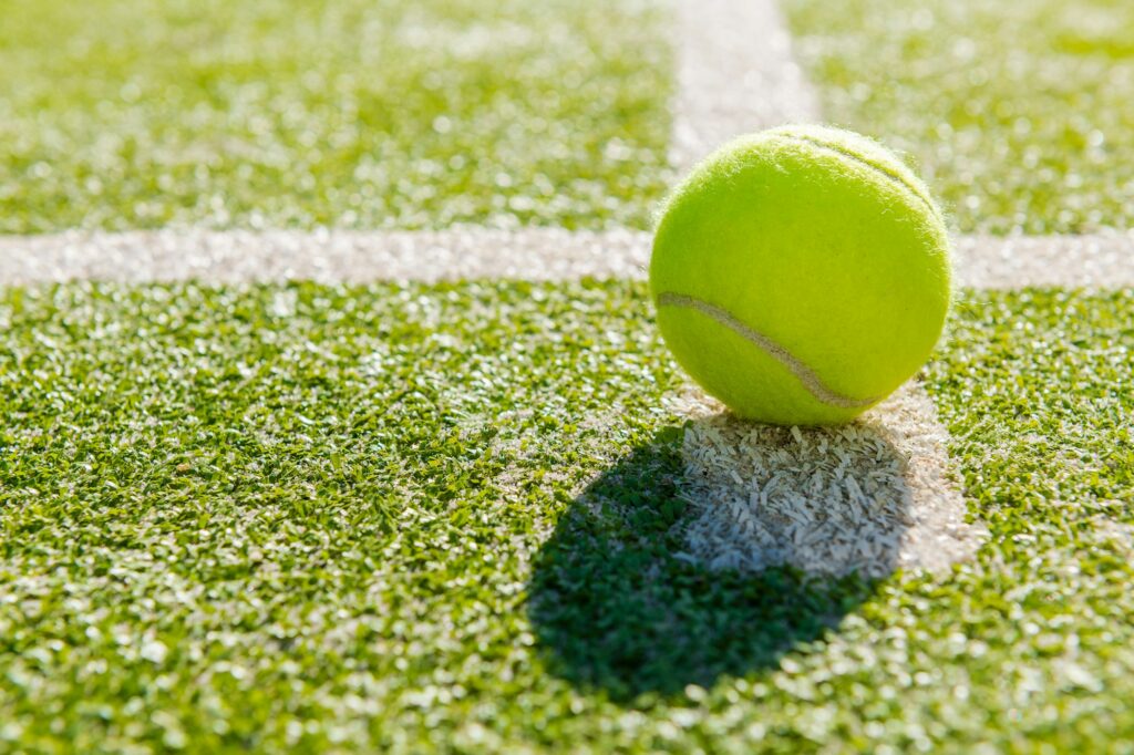 yellow tennis ball in court on artificial grass